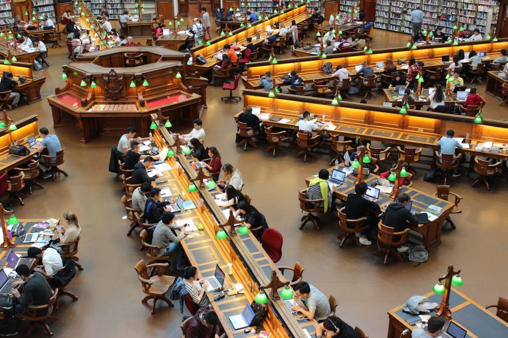 library-high-angle-photro-159775 A lively university library scene with students studying diligently at wooden desks.