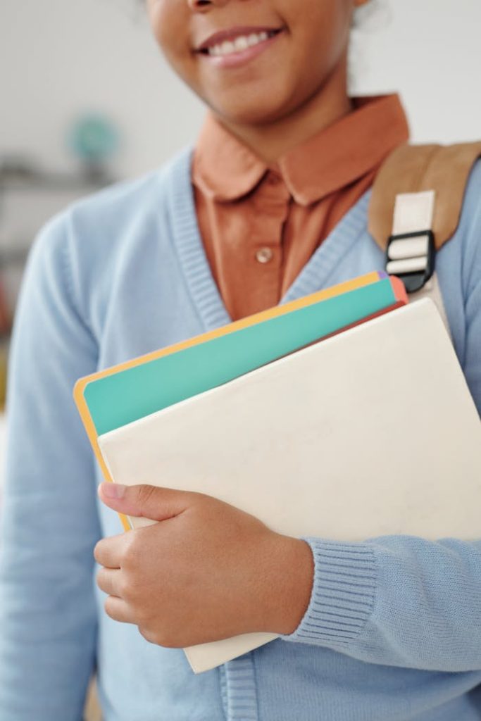 woman-holding-school-materials-5211436 African American student with textbooks, ready for school. Ideal for educational themes.